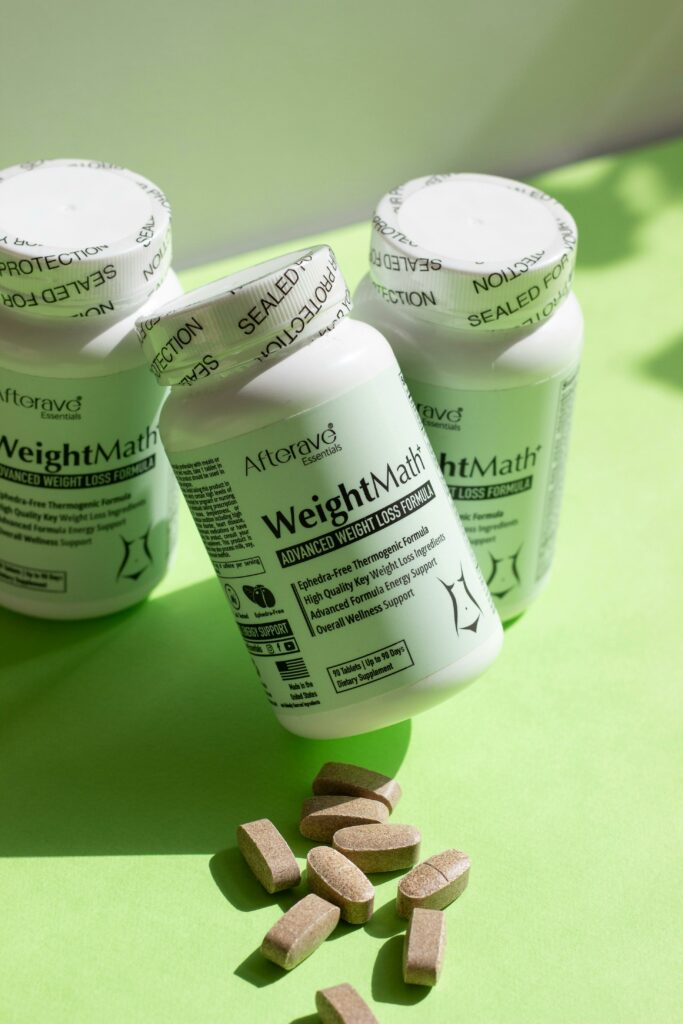 Three bottles of weight loss supplements with tablets on a green surface.